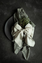 Eco-friendly wedding decor featuring gray cotton napkins on a placesetting tied with a champagne color ribbon bow. Hand-loomed and plant dyed cotton napkins.