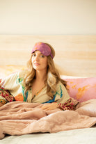 model wearing botanical silk sleep eye mask laying in a crate and barrel bed wearing an anthropolgie robe